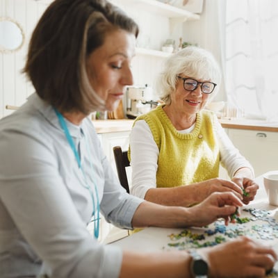 Adult woman and senior woman working on a puzzle.