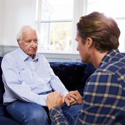 Senior man and adult son holding hands.