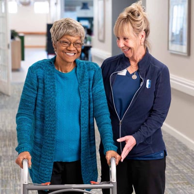 A senior woman walking with a walker.