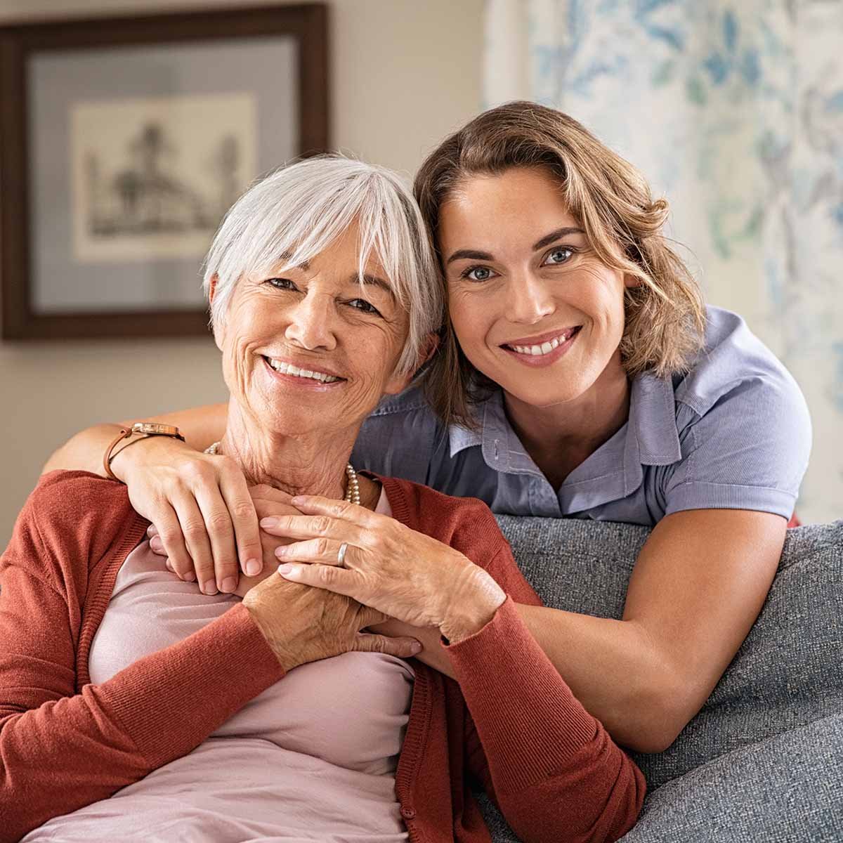 Senior smiling with her daughter while sitting on her couch