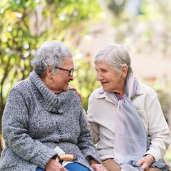 Senior ladies talking on a park bench.