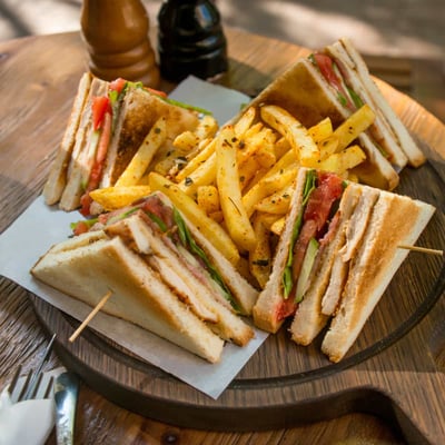 Fresh club sandwich with ham, cheese and potatoes on a wooden table.