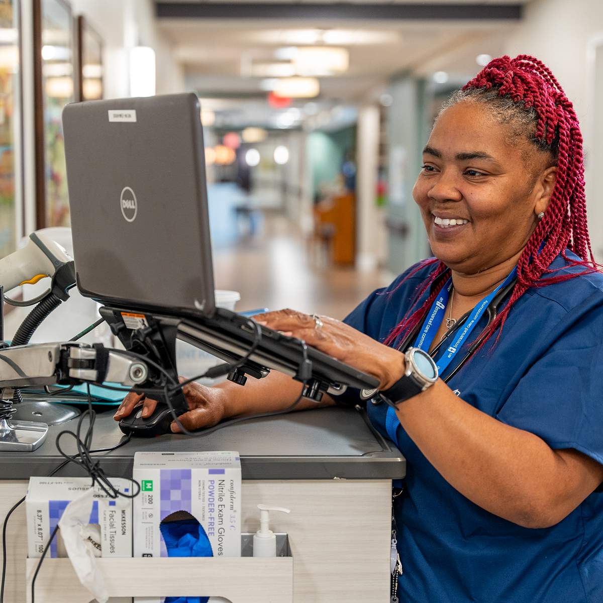 A nurse smiles as she works from her computer.