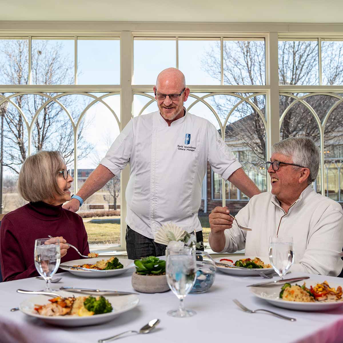 An Immanuel chef converses with several residents during their meal. 