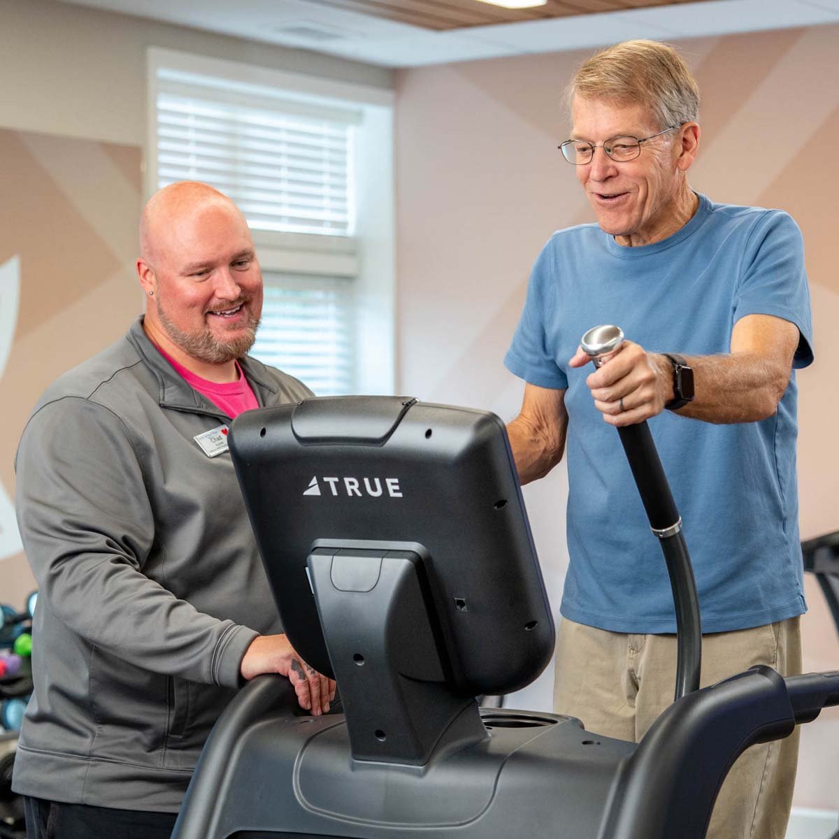 employee-helping-senior-on-ellipitical-1200x1200