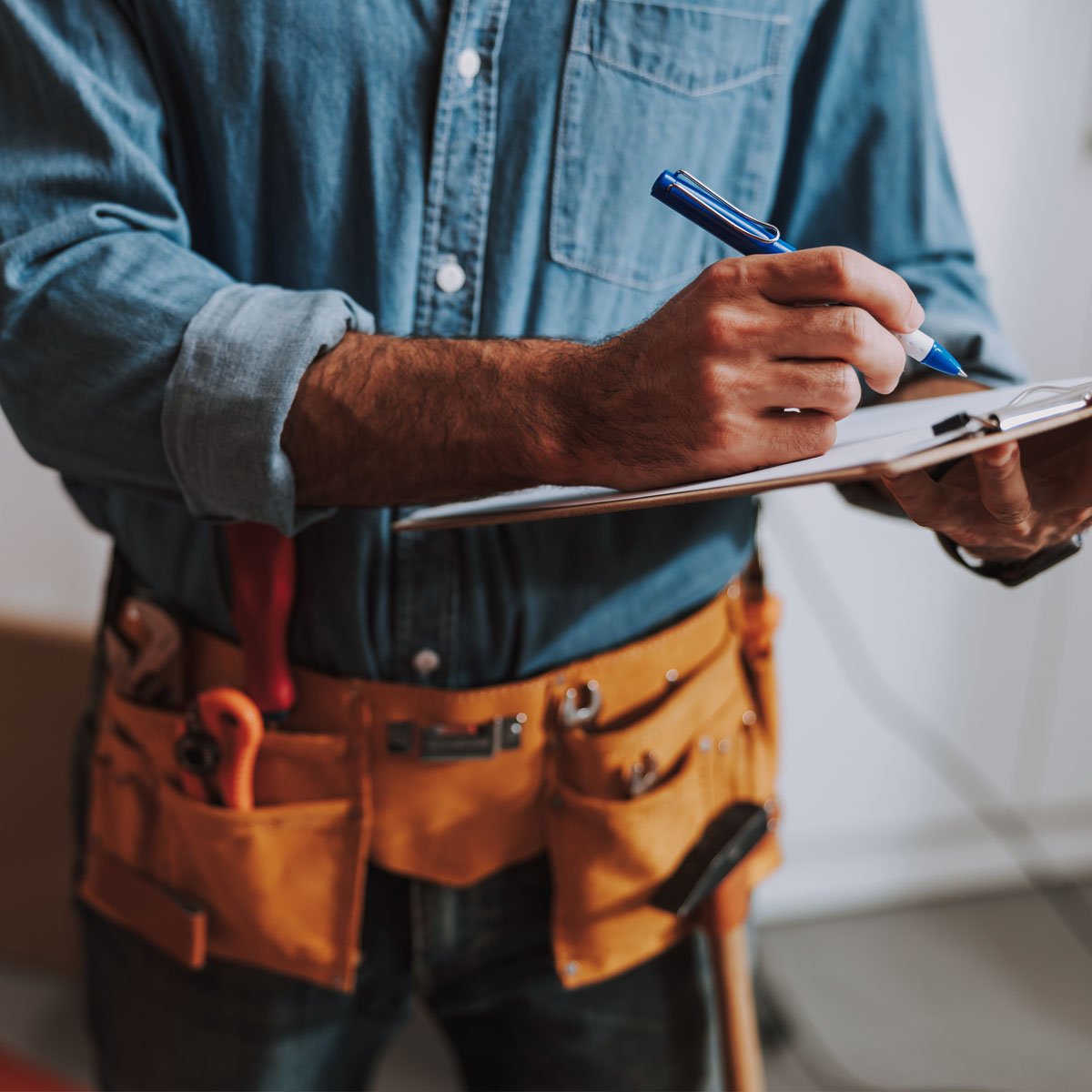 A home contractor writes on a clipboard.