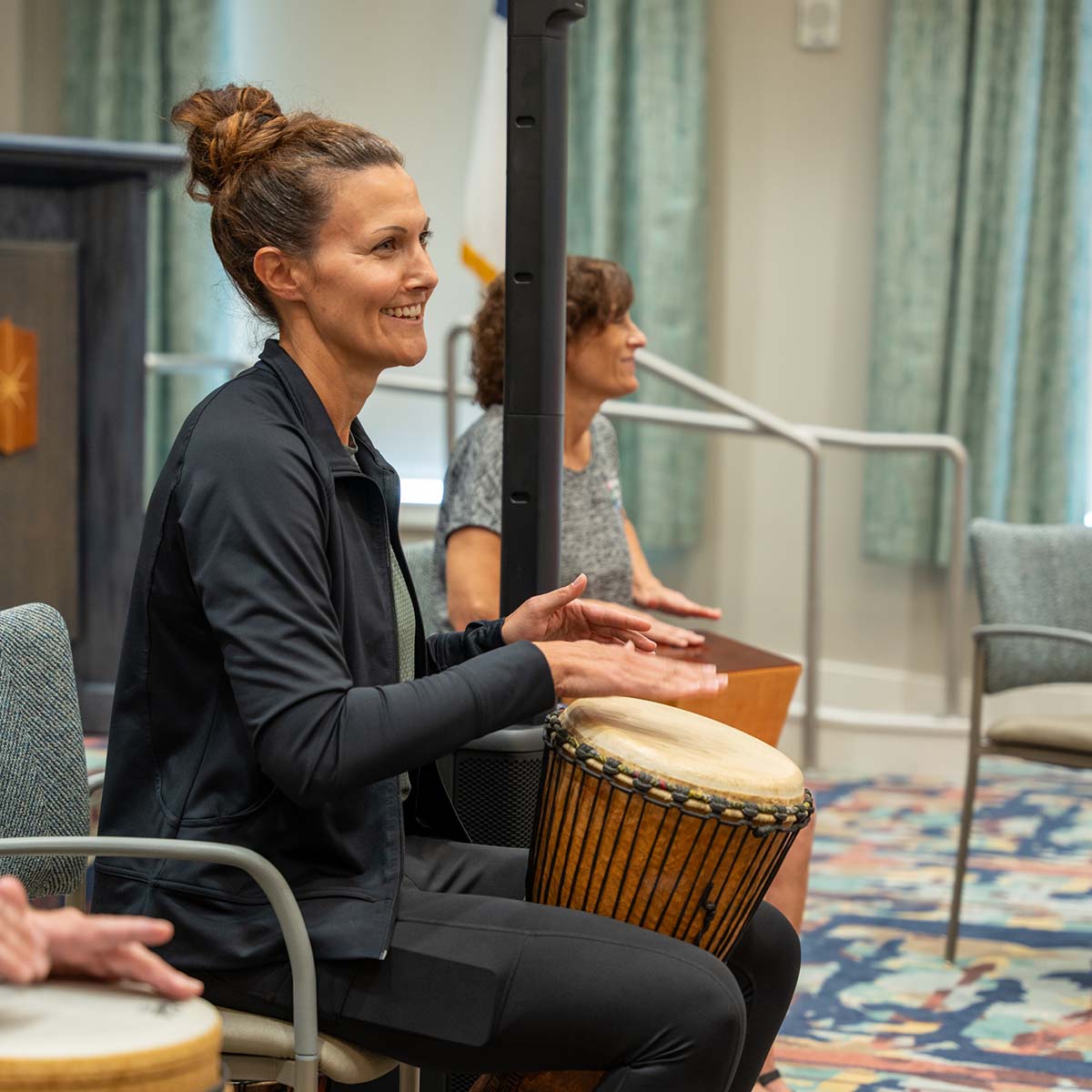 A life enrichment coordinator playing a hand drum. 