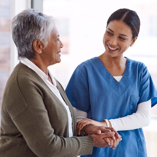 A nurse smiles while walking with a senior.