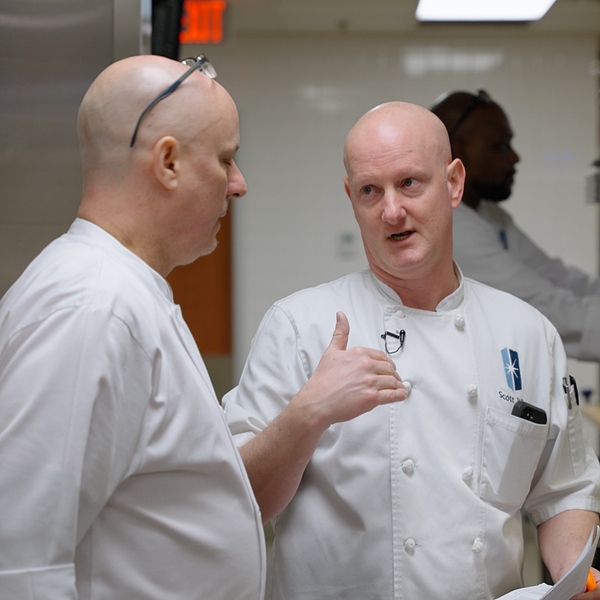 Two Immanuel chefs working together in a commercial kitchen.