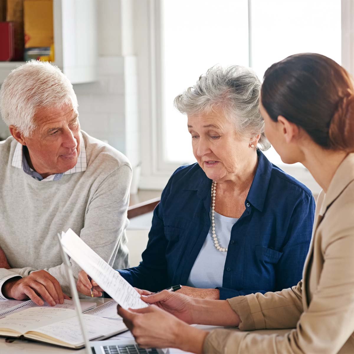 A senior couple reviews paperwork with a consultant.