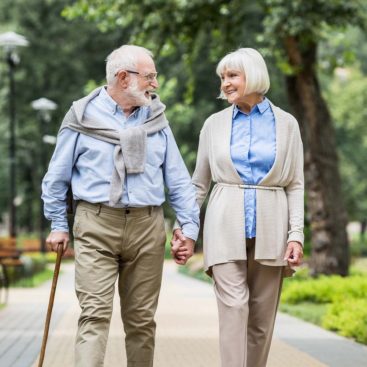 A senior couple walk together in a park.