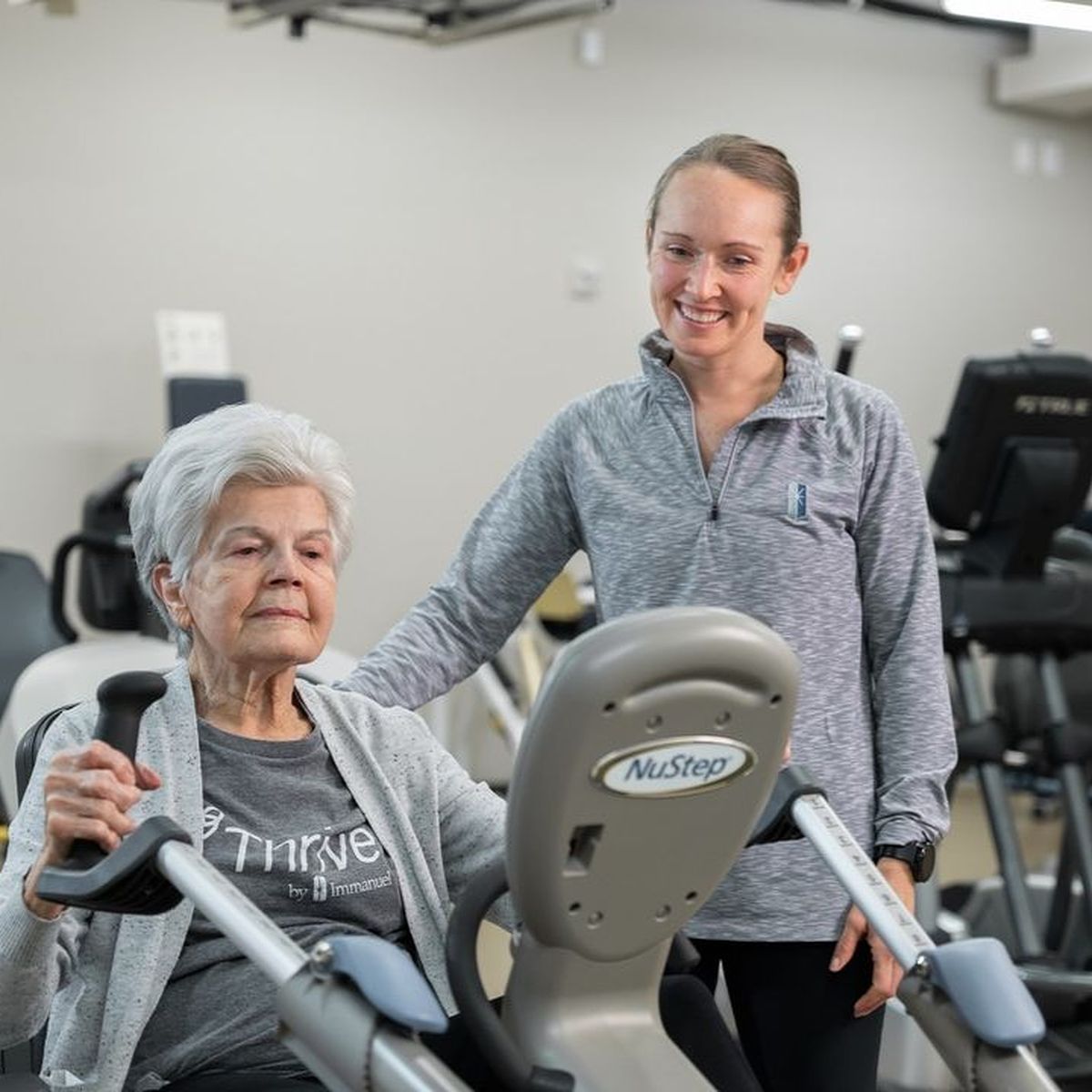 Immanuel instructor helping elderly resident workout.