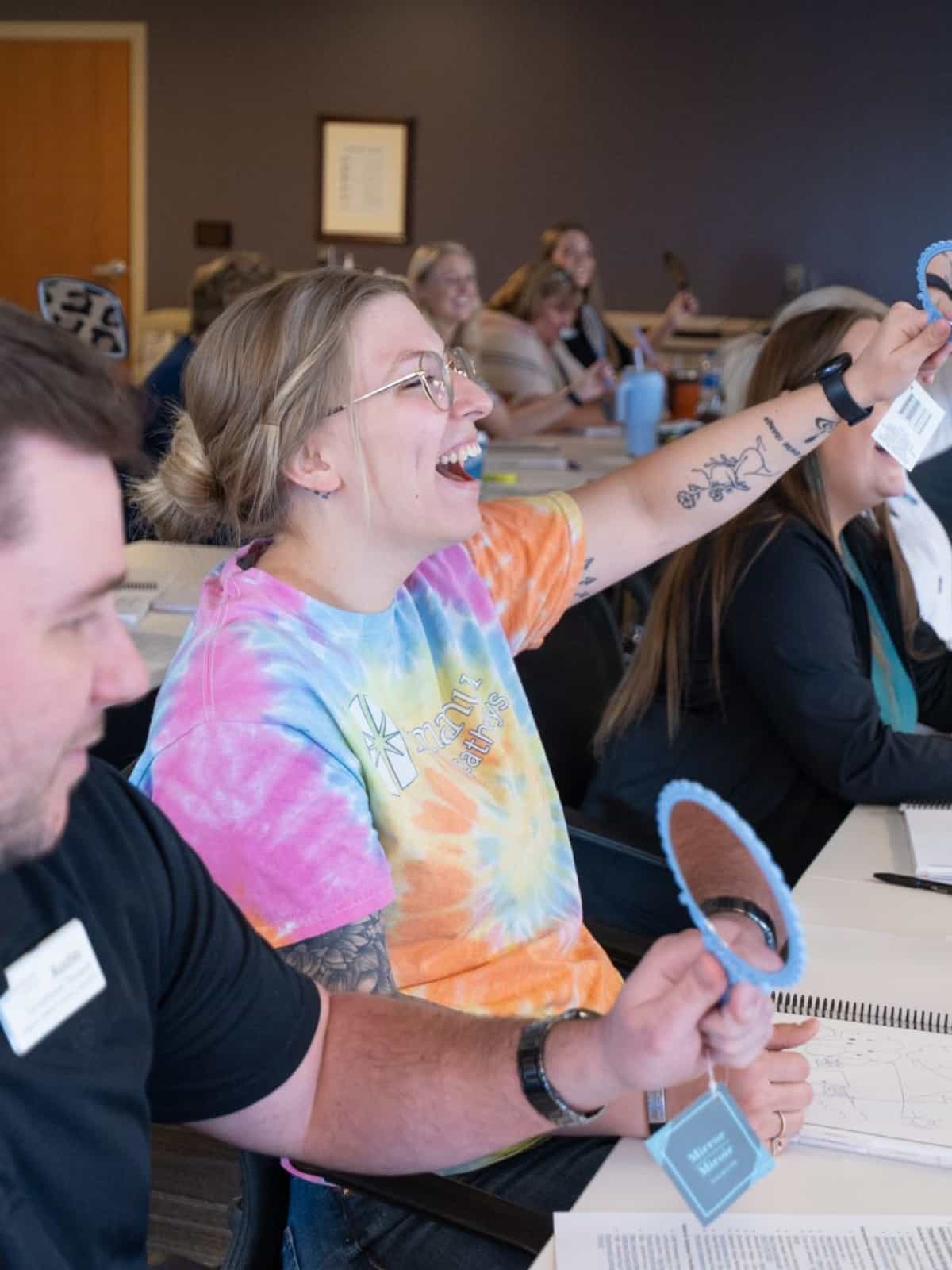 An Immanuel employee smiles and raise here hand during an employee training session.