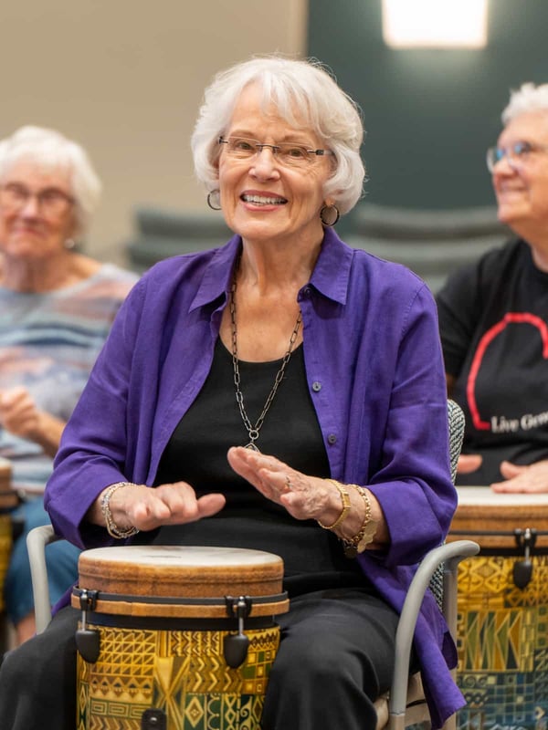 A group of residents are smiling while playing drums together
