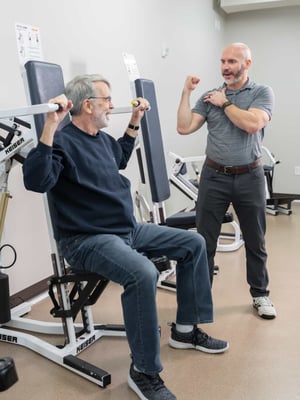 A Thrive wellness specialist instructs a senior as he uses exercise equipment.