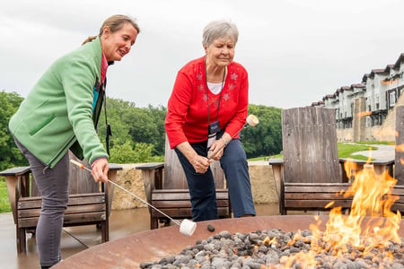 Beth Nodes, Immanuel Vice President of Experience, roasts marshmallows with a resident during an Immanuel Explorers trip to the Arbor Day Lodge in Nebraska City.