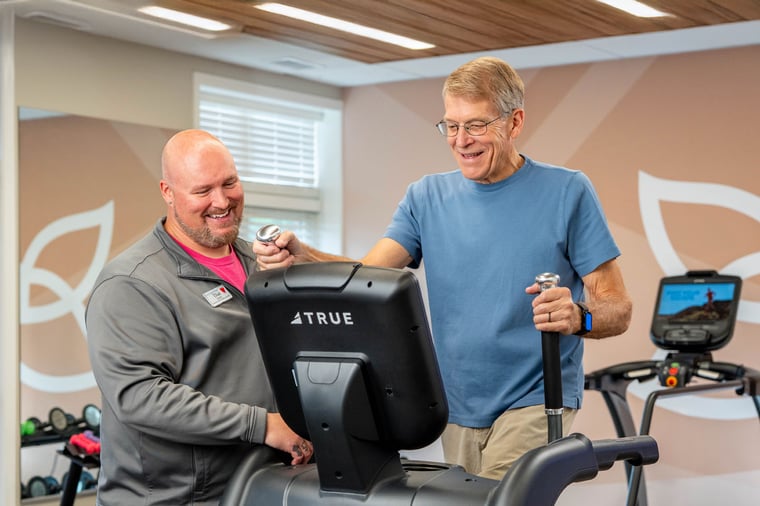 A Thrive Wellness staff member assists a resident with his workout at Pacific Springs.