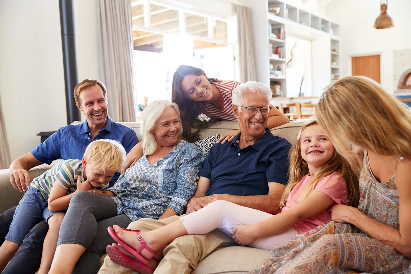 A multi-generational family sits together on a couch.