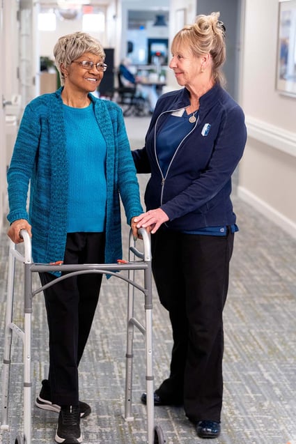 An Immanuel employee helps a long-term care resident walk down the hallway at The Lighthouse in Omaha.