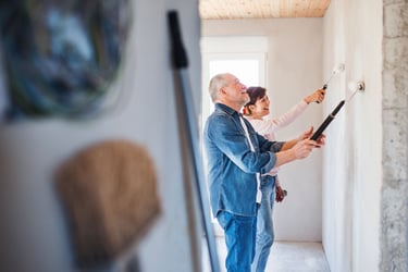 Senior couple painting a wall in their home.