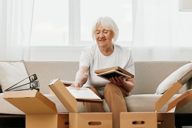 Senior woman packing boxes while sitting on her couch.