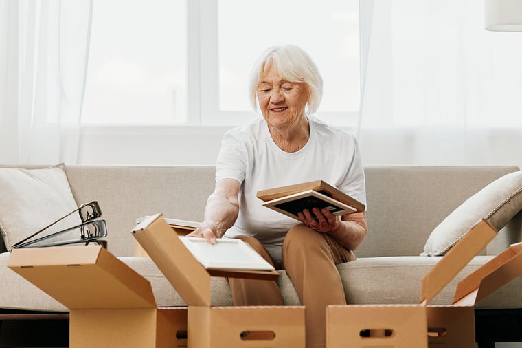 Senior woman packing boxes while sitting on her couch.