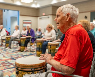 An Immanuel resident plays the hand drum in a group with other residents.