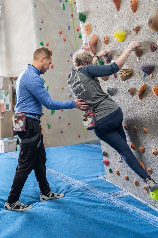 Thrive team member working with a resident on a rock climbing wall.