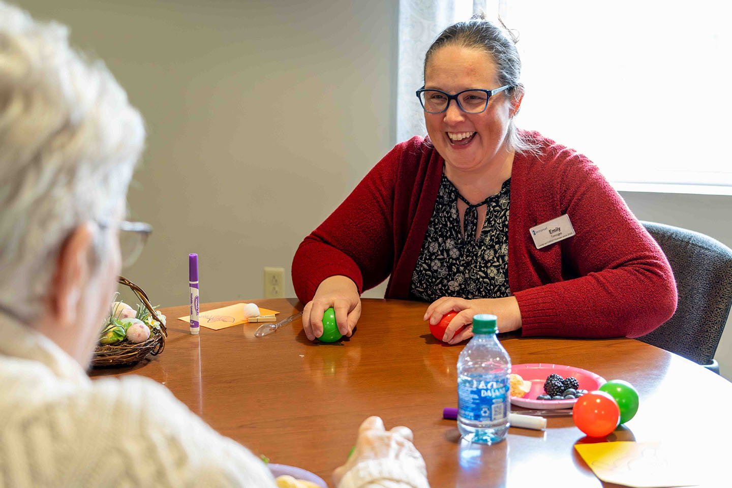 A staff members participates in a Brain Fitness activity with a senior woman.