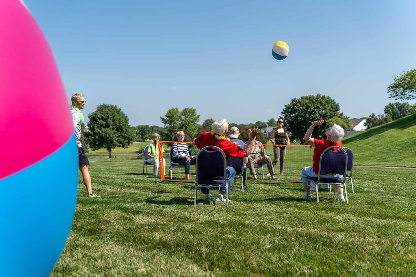 A group of seniors play chair volleyball outside.