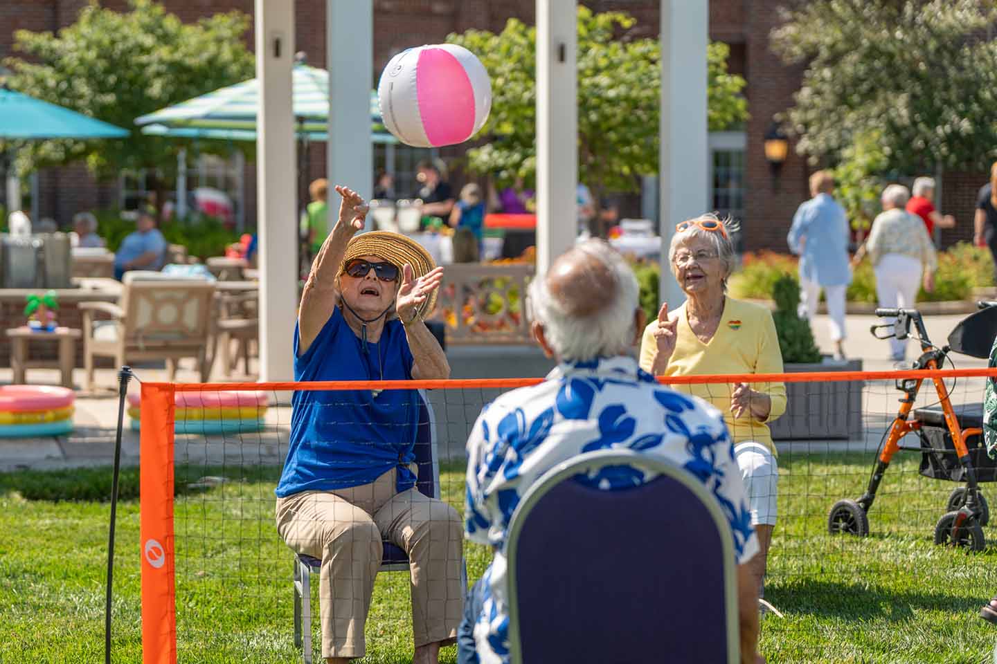A group of seniors play a game of chair volleyball outside.