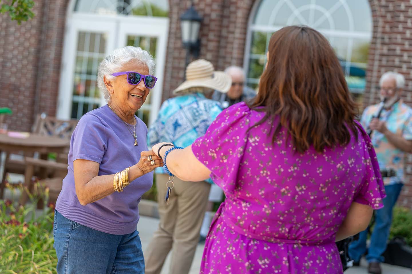 A senior woman and a middle-aged woman dance to live music. 