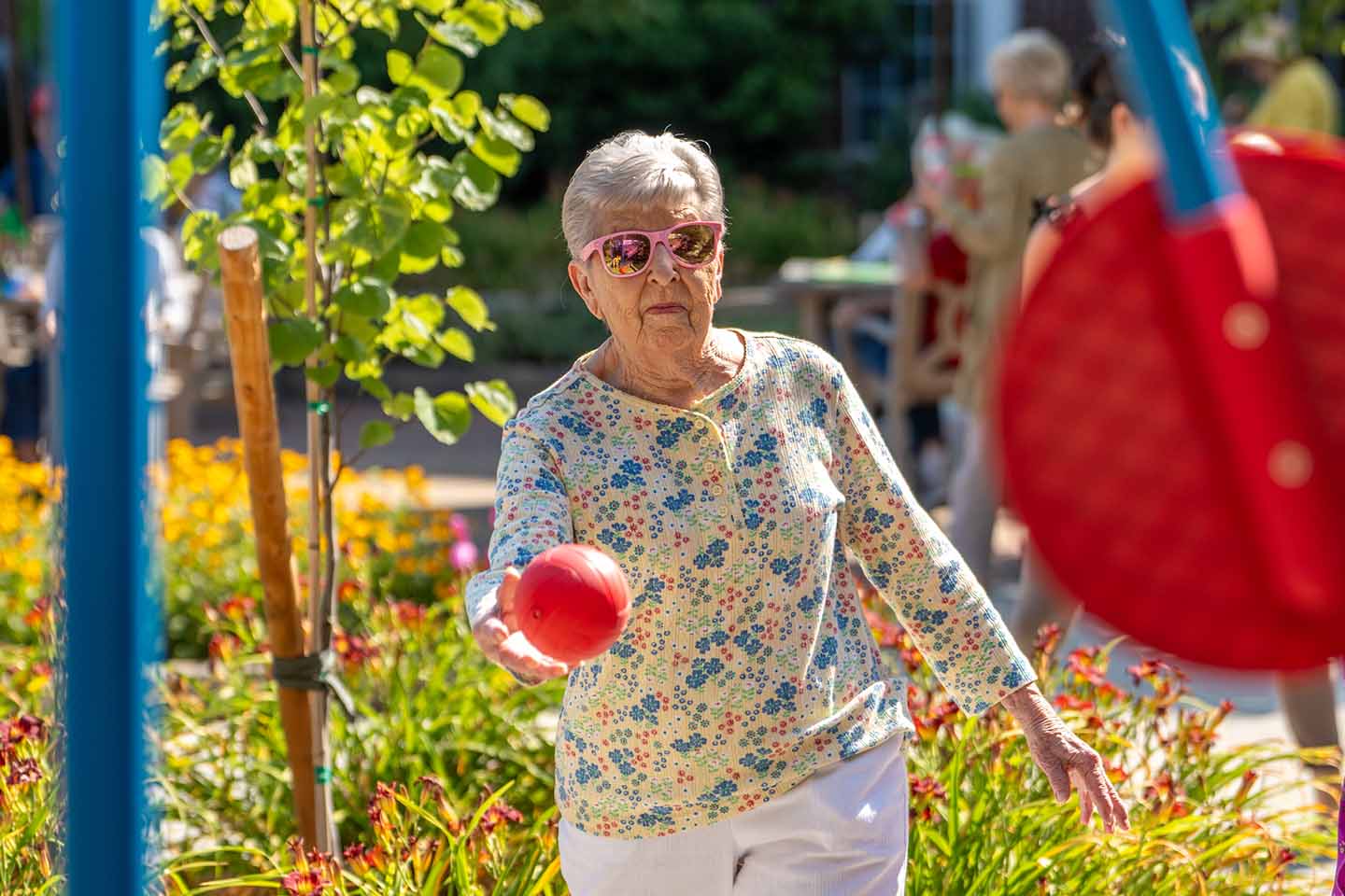 A senior woman throws a ball at a target.