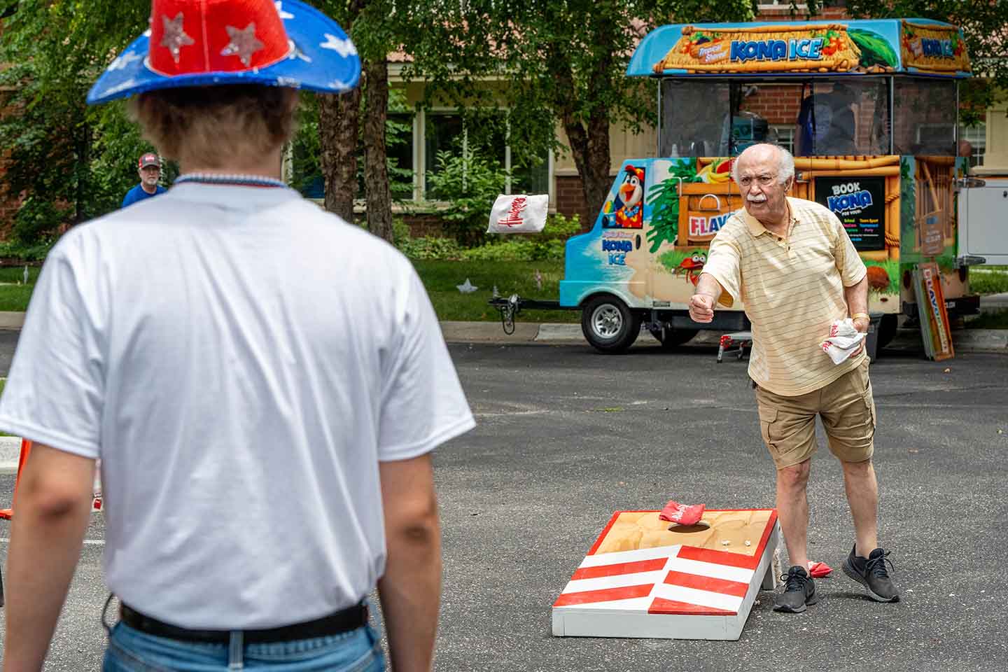 A senior male plays bean bag toss.