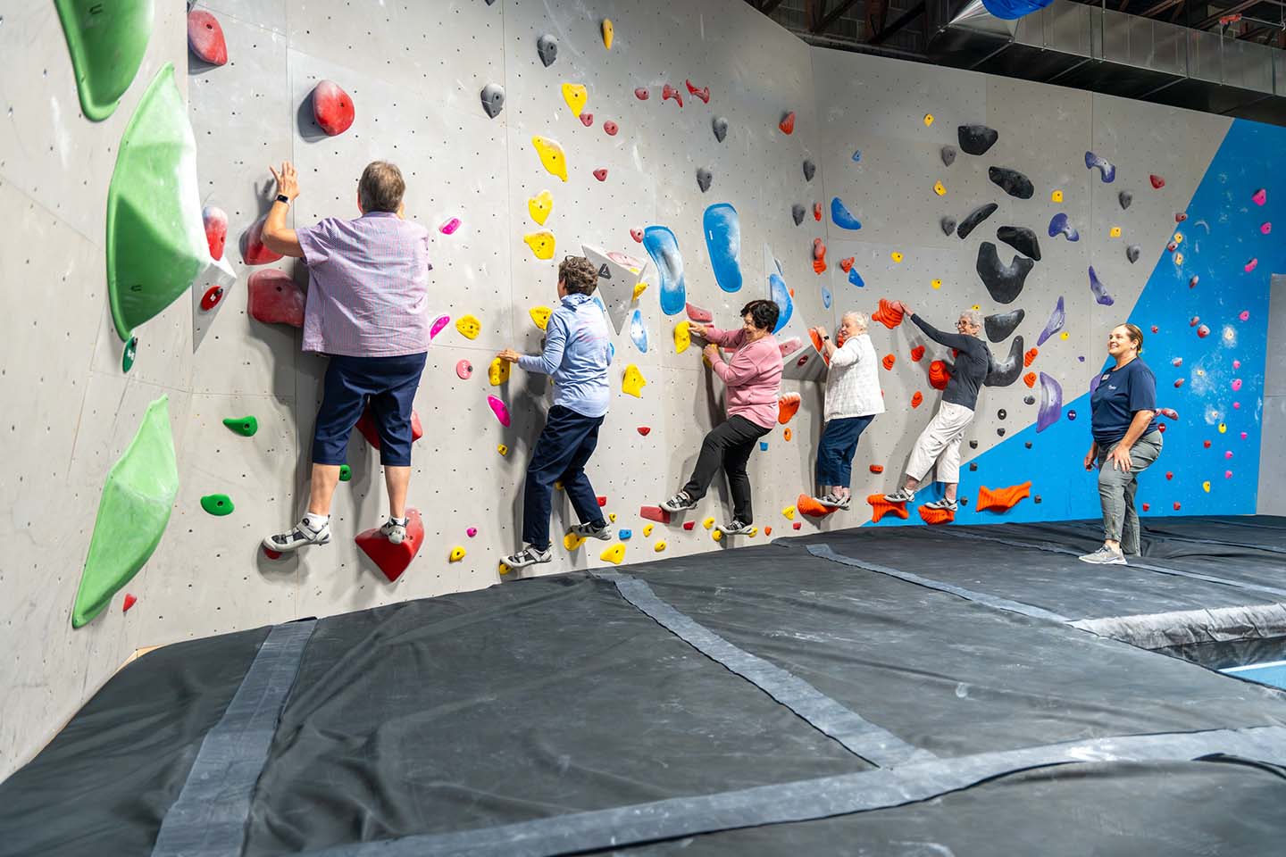 A group of seniors climb an indoor rock wall.