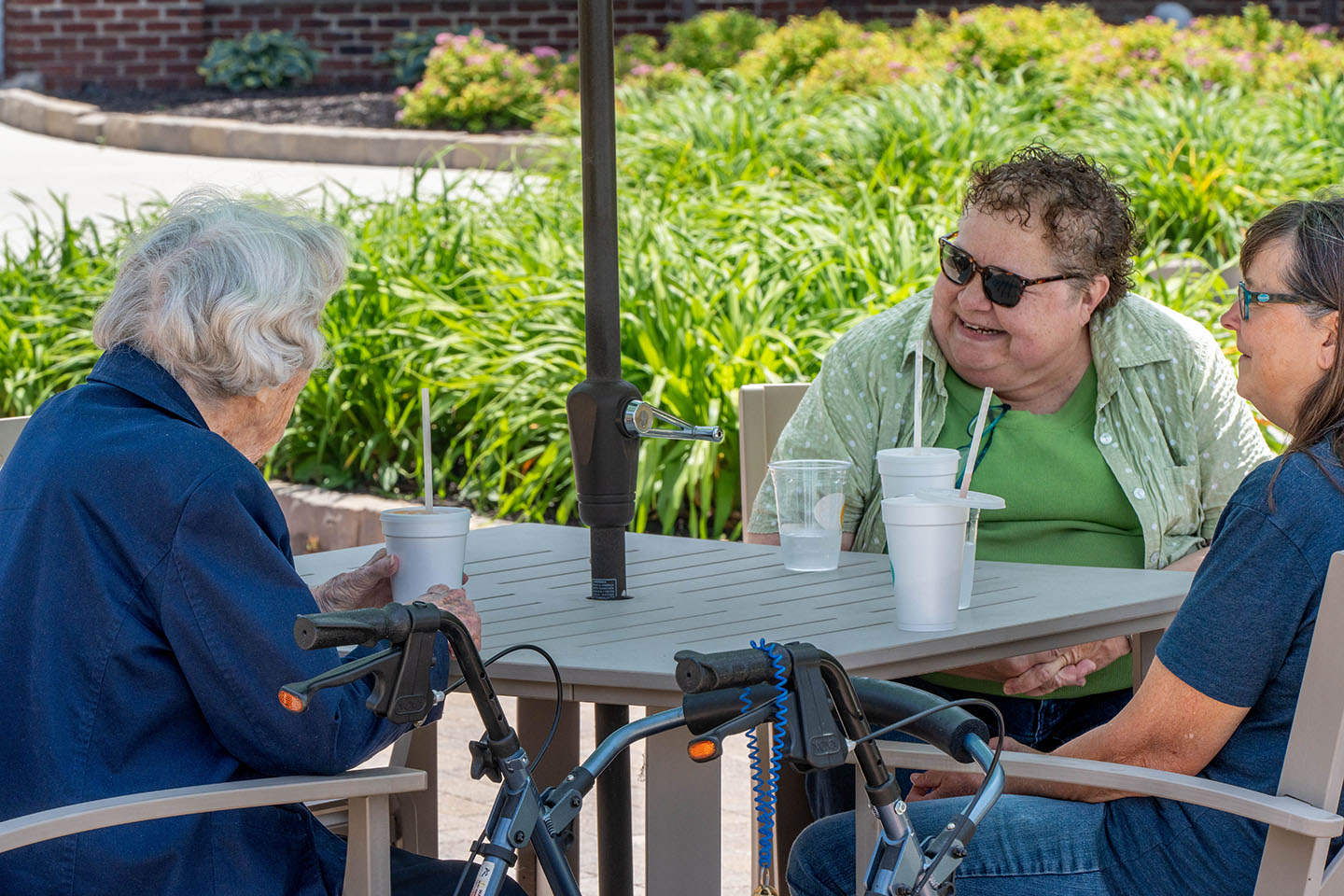 A group of seniors sit together at a patio table.