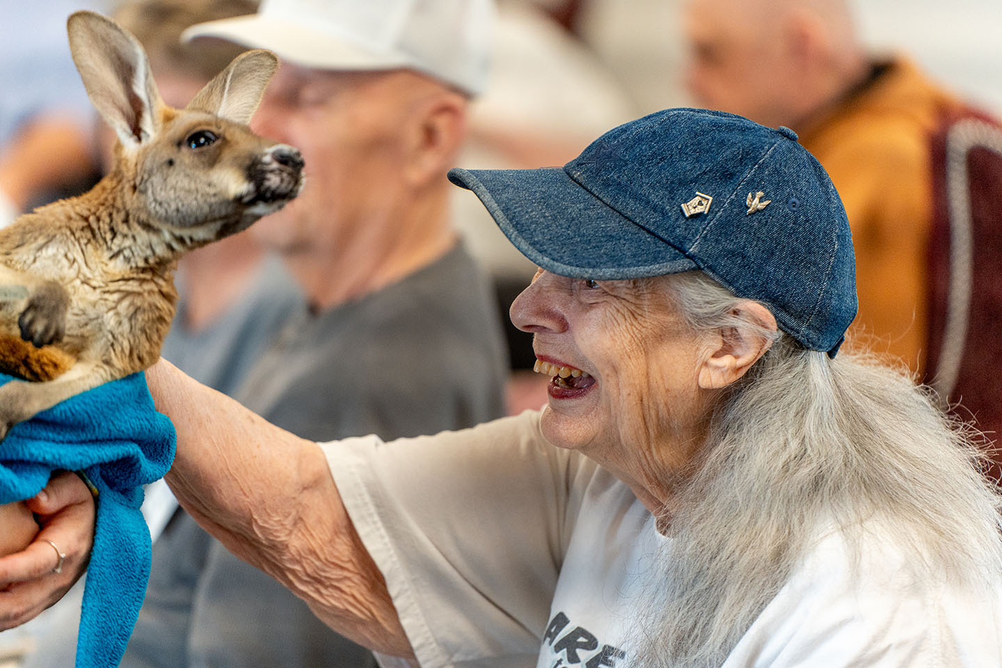 A senior woman pets a joey.